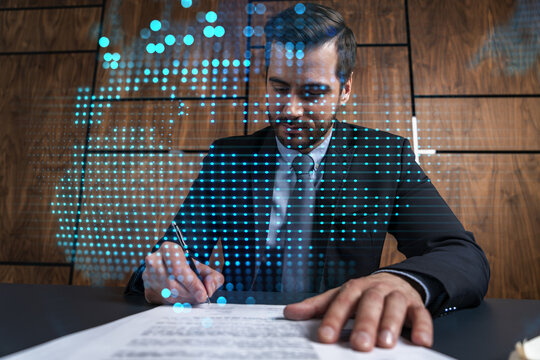 Businessman in office signs contract and world map hologram. Double exposure. Formal wear. International business connection.