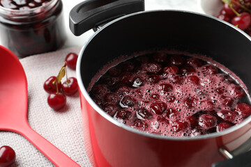 Pot with cherries in sugar syrup on table, closeup. Making delicious jam