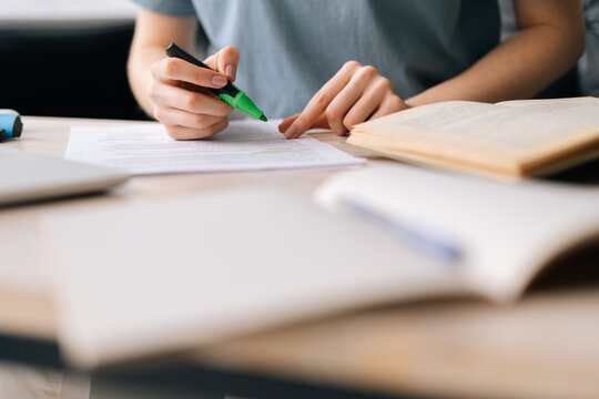 Close-up of hands of unrecognizable businesswoman highlighting important things in paper document with marker. Business lady working at home office.