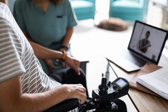 Quadriplegic man and healthcare worker on video conference with doctor