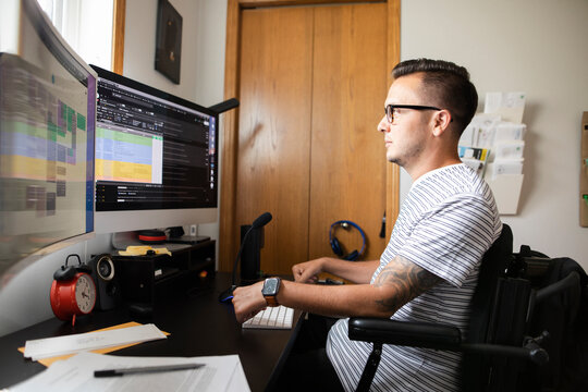 Man in wheelchair working at computer at home