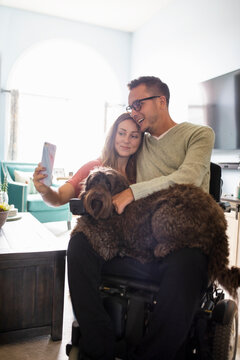 Quadriplegic man and girlfriend taking selfie with pet dog
