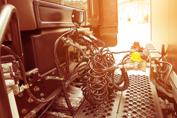 Coiled control and electrical cables connect the cab and semi-trailer of the truck. Warm editing with pop filtered sunshine.