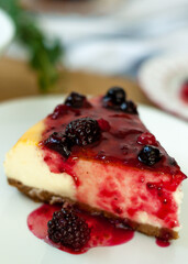 Classic New York cheesecake portion with strawberry jam covered on a white dish.