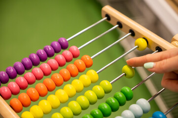 Closeup female hand calculating with balls on wooden rainbow abacus for number calculation. The...
