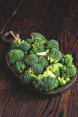 Fresh green organic broccoli vegetable on a woofen cutting board on a dark rustic wooden background. top view. copy space