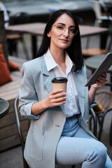 serious businesswoman holding tablet and cofee at city cafe - 367609235