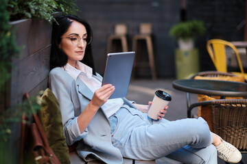 serious businesswoman holding tablet and cofee at city cafe - 367609280