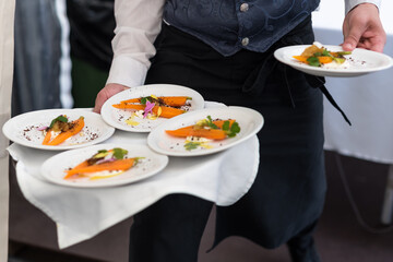 Braised Carrot with Sour Cream, White Fish Roe and Petals. Waiter Serving Food