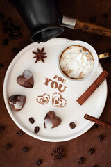 Cup of fresh hot coffee, words FOR YOU , cezve, coffee beans, chocolate candy in the shape of a heart. Selective focus. Top view. Concept of valentines