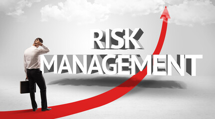 Rear view of a businessman standing in front of RISK MANAGEMENT inscription, successful business concept