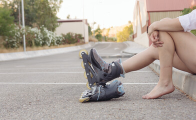 Blonde girl in a white blouse, jeans and skates tying her laces. Roller-skating concept
