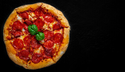 Pepperoni Pizza with Mozzarella cheese, salami, Tomato sauce, pepper, Spices. Italian pizza on Dark grey black slate background