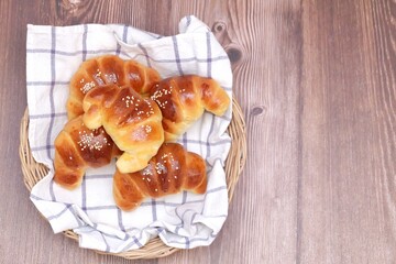 A group of homemade croissants in a basket top view on old wooden dinning table background