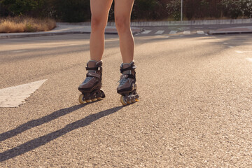 Close up of Blonde girl in white blouse and jeans skating in the city at sunset. Roller-skating concept