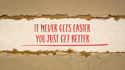 It never gets easier, you just get better - inspirational handwriting on handmade paper, business, education and personal development concept, web banner