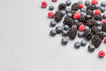 Blackberries, raspberries and blueberries on gray background.