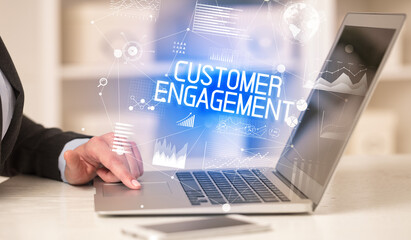 Side view of a business person working on laptop with CUSTOMER ENGAGEMENT inscription, modern business concept
