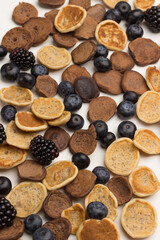 Mini pancakes and berries on white background.