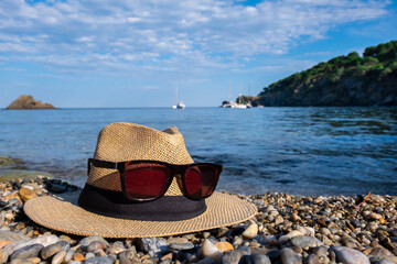 Close-up of a hat and sun glasses. Blue sea and sky.