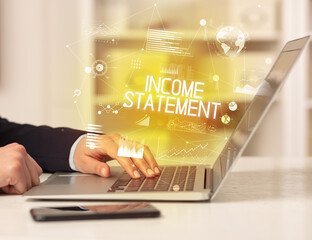 Side view of a business person working on laptop with INCOME STATEMENT inscription, modern business concept