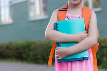 Fotobehang slim schoolmeisje buitenshuis. Kleine student houdt notitieboekjes vast © Albert Ziganshin