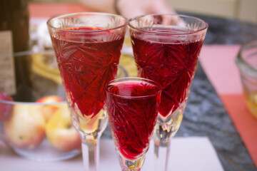 Three goblets with red liquid on a blurred table background. Wine, juice, beverage.