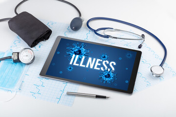 Tablet pc and doctor tools on white surface with ILLNESS inscription, pandemic concept