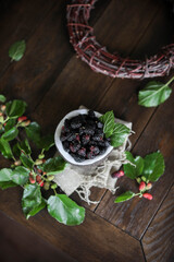 Mulberry in a coconut shell with green leaves on a wooden table. Summer berries.