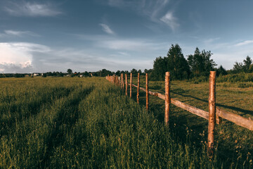 Fototapeta na wymiar Wooden fence on nice green meadow