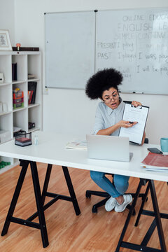 Giving online class. Young afro american woman sitting at her workplace at home and teaching English online, explaining rules of English grammar