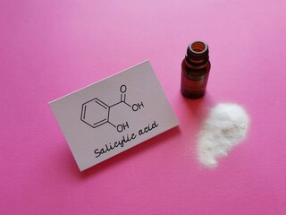 Structural chemical formula of salicylic acid molecule with white powder and a cosmetic bottle....