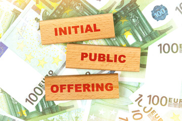 Against the background of euro bills, the text is written on wooden blocks - initial public offering