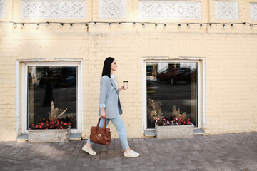 smiling pretty businesswoman holding cofee walking street - 367621210