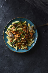 Healthy vegetarian homemade food. Pasta with wild forest mushrooms and green beans in turquoise plate on black background copy space