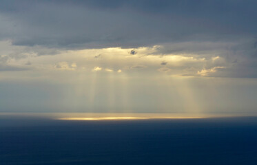 Sun rays shining through clouds at sea 