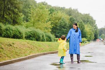 Mother and child, boy, playing in the rain, wearing boots and raincoats