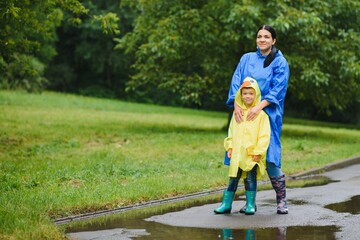 Mom and son in raincoats have fun together in the rain. concept of family vacation and happy childhood.