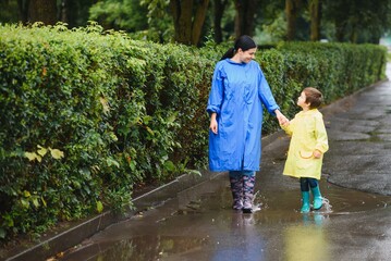 Mother and child, boy, playing in the rain, wearing boots and raincoats