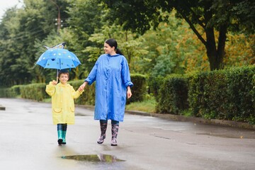 Mother with son walking in the rain under the umbrella