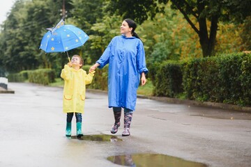 Mother with son walking in the rain under the umbrella