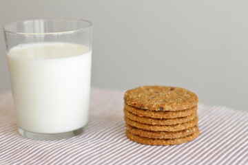 Oat cookies with glass of milk for breakfast on table cloth and blue flower on background, rustic healthy food 