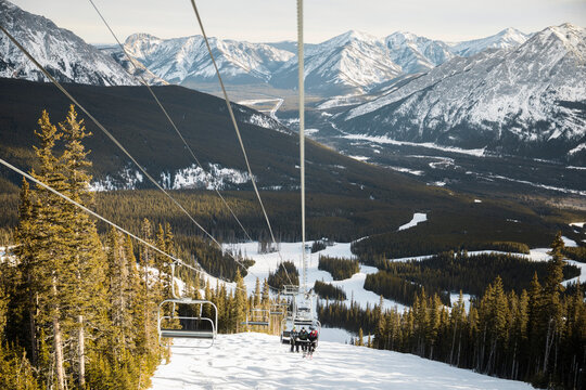 Friends Riding Ski Lift Above Snowy Mountain Ski Slope