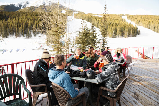 Skier friends relaxing and drinking beer on sunny ski resort patio
