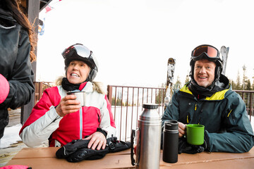 Happy skier couple drinking coffee on ski resort patio