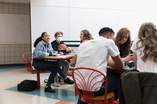 High school student in flu mask with friends in cafeteria