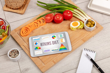 Organic food and tablet pc showing ATKINS DIET inscription, healthy nutrition composition