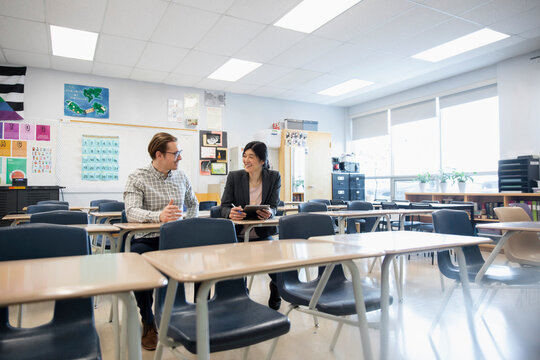 High school teachers with digital tablet talking in classroom