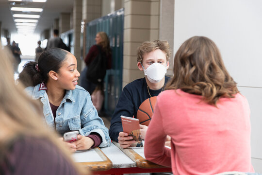 High school boy in flu mask talking with friends