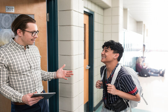 High school teacher talking with student in corridor